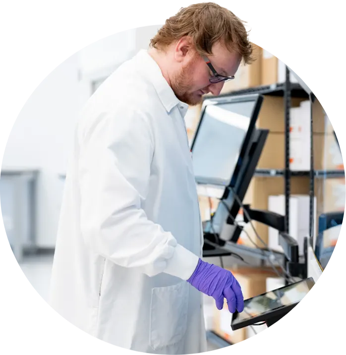 Gray background with blue abstract wave intersecting a circle containing a close-up image of a male employee in the lab